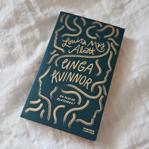 Unga kvinnor - Säljer boken 'Unga kvinnor' av Louisa May Alcott. Omslaget är mörkgrönt med guldiga illustrationer och text. En älskad klassiker om systrarna Marchs liv i 1860-talets USA. Perfekt för dig som gillar klassiska romaner.
