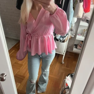 Rosa omlottblus från Missay - Säljer en rosa omlottblus från Missay med knyt i midjan och volang nertill. Blusen har långa ärmar och v-ringad halsringning. Perfekt för dig som vill ha en feminin och trendig topp.