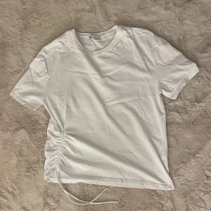 Vit t-shirt med snörning från Zara - Vit t-shirt från Zara med korta ärmar och snygg snörningsdetalj. Perfekt för dig som gillar stilrena basplagg med en twist. Den är endast testad 💕