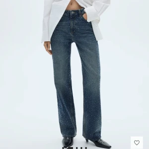 Blå jeans med glittriga detaljer - Snygga blå jeans med raka ben och glittriga prickar över hela byxan. Klassisk femficksmodell med hög midja och knappgylf. Perfekta för dig som vill sticka ut lite extra.