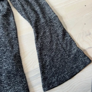 Mörkgrå melerad långärmad tröja från KappAhl - Mysig mörkgrå melerad långärmad tröja från KappAhl. Utsvängda armar. Tröjan har en rund halsringning och är tillverkad i ett mjukt, stretchigt material. Perfekt för en avslappnad och bekväm stil.