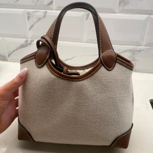 Sommar handväska H&M - Den perfekt sommar väskan. Helt oanvänd men med en liten spricka (visas på bild 4) bristen syns inte alls. Prislapp kvar! Original pris 300