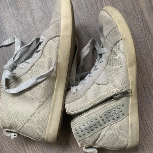 Snygga beiga höga sneakers med dragkedja och nitar - Gråa sneakers i st 40 men passar mig som har 39 också! Super snygga skor men fina detaljer. Väl använda sen innan men i bra skicka. Säljer pga att de inte används så mycket längre💖 Pris kan diskuteras😇