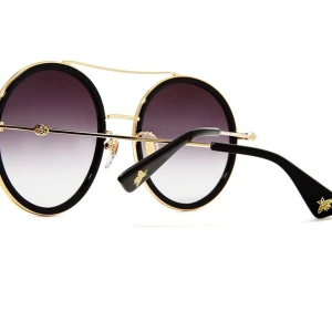 Runda solglasögon från Gucci med gulddetaljer - Snygga runda solglasögon från Gucci med svart båge, guldfärgade detaljer och mörktonade glas. Klassisk design med en modern twist och diskret Gucci-logo på sidan. Perfekta för att lyfta vilken outfit som helst.