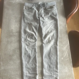 Grå slim fit jeans från 157 - Snygga grå jeans från 157 i slim fit-modell. Klassisk femficksdesign med dragkedja och knapp framtill. Perfekta för dig som gillar en smalare passform och stilren look.