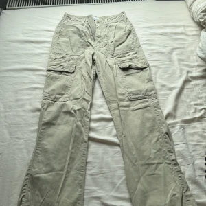 Beiga cargopants med fickor - Säljer ett par beiga cargopants med flera stora fickor på sidorna och framtill. Byxorna har en rak passform och är perfekta för en avslappnad stil. Materialet känns slitstarkt och bekvämt.