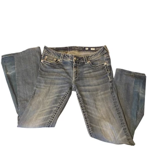 Blå broderade jeans från Miss Me - Säljer ett par blå jeans med vit söm, från Miss Me med snygga broderade detaljer på bakfickorna och bootcut-passform. Jeansen har klassisk femficksdesign, knappar och dragkedja framtill. Byxorna var från början straight leg och har jag själv sytt ut de till bootcut med det kan man lätt sy tillbaka då jag endast spretat dem, på bild 4 kan man se ett pyttelitet hål men det syns knappt . Skriv gärna vid frågor🤗