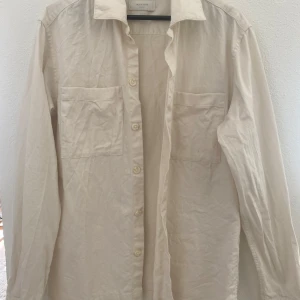 Vit skjorta från Jack & Jones Premium - Klassisk vit skjorta från Jack & Jones Premium med två bröstfickor och knäppning framtill. Skjortan har lång ärm och är tillverkad i ett mjukt bomullstyg. Perfekt för en clean och stilren look.