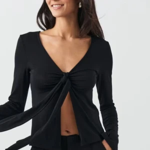 Topp med knyt från Gina Tricot - Trendig svart långärmad topp från Gina Tricot med djup v-ringning och knyt framtill. Toppen finns inte att köpa längre och jag har använt min max 3-4 gånger, tröjan är storlek L men passar även M. Skriv om ni har några frågor💕