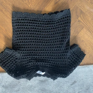 Svart stickad topp från Mango - Säljer en svart stickad topp från Mango med korta ärmar och ett luftigt, hålmönstrat material. Perfekt att styla över ett linne eller bikini. Ribbstickade kanter vid hals, ärmslut och nederkant.