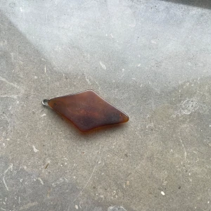 Brun vintage brosch i plast - Unik brun brosch i plast med oregelbunden form och metallspänne på baksidan. Perfekt som accessoar för att ge din outfit en retro touch.