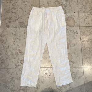 Beiga linnebyxor  - Säljer ett par beiga linnebyxor från H&M med regular fit. Byxorna har resår i midjan samt fickor på sidorna och en bakficka. Perfekta för varma dagar och en avslappnad stil. Köpt för 350kr, mitt pris 100kr.