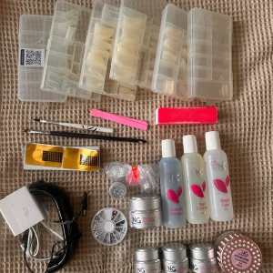 Stort nagelkit med gel och dekorationer - Komplett nagelkit med flera burkar gel (clear, primer, vit, rosa), nail cleaner, brush care och clean off solution. Inkluderar nageltippar i olika storlekar, penslar, filar, buffer, dekorationer, former . Perfekt för att skapa egna gelnaglar hemma.  Kommer tyvärr inte kunna ta fler bilder då det tar upp alldeles för lång tid men allt går att söka upp. Medkommer glitter, 2 uv-lampor mm..  Det är i befintligt skick: vissa grejer är oöppnade medans vissa är halvfulla.   Nypris är ca 2500
