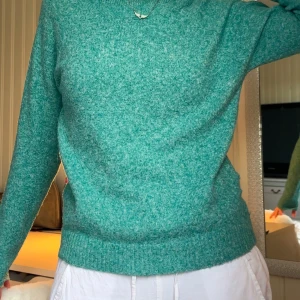 Turkos stickad tröja - Mysig turkos stickad tröja med rund halsringning och långa ärmar. Perfekt för kyligare dagar och enkel att matcha med olika outfits. Tröjan har en klassisk passform och är superbekväm.