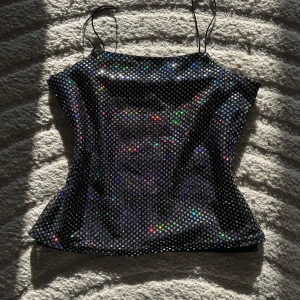 Glittrig svart linnetopp - Säljer en svart glittrig linnetopp från id:X med tunna axelband. Det står ingen storlek men skulle säga att den passar s. Perfekt nu till sommaren eller som festtopp!