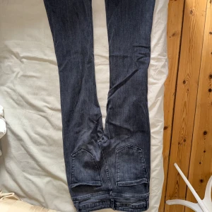 Grå jeansbyxor från Zara - Säljer ett par grå jeansbyxor från Zara som är bootcut. Byxorna har slitningar på båda benen för en trendig look. Perfekta för dig som gillar en avslappnad eller uppklädd och cool stil.