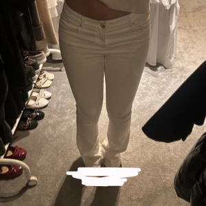 Vita jeans - Säljer ett par vita jeans med låg midja. Byxorna har klassisk femficksdesign och stängs med dragkedja och knapp framtill. Perfekta att matcha med crop tops eller stickade tröjor.