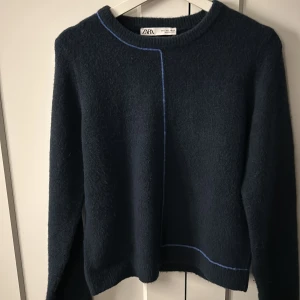 Mörkblå stickad tröja  - Säljer en mörkblå stickad tröja från ZARA med rund halsringning och dekorativa blå sömmar framtill och baktill. Tröjan har lång ärm och en enkel, stilren design som passar perfekt till många outfits. Är i storlek L men skulle säga att den mer är som en S möjligen M