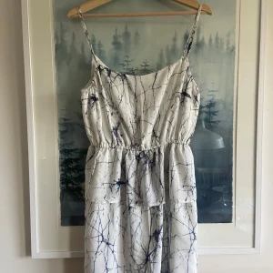 Vit och blå mönstrad klänning från Twist & Tango - Säljer en vit klänning med blått abstrakt mönster från Twist & Tango. Klänningen har smala axelband, markerad midja och luftig passform. Perfekt för varma dagar och har en lätt, somrig känsla.