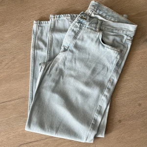 Ljusblå jeansbyxor från SWEETSKTBS - Säljer ett par ljusblå jeansbyxor från SWEETSKTBS med klassisk femficksdesign och raka ben. Jeansen har gylf med dragkedja och knapp, samt detaljerade sömmar i kontrastfärg. Perfekta för en avslappnad stil.