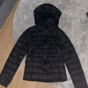 Svart pufferjacka från Only med huva - Säljer en svart pufferjacka från Only med huva och dragkedja framtill. Jackan är lätt vadderad och har en klassisk, enkel design som passar till många olika stilar. Perfekt för kyligare dagar.