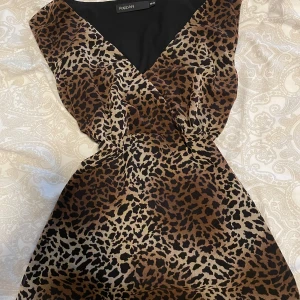 Leopardmönstrad omlott tröja - Säljer en snygg leopardmönstrad omlott top från tidigt 2000-tal med v-ringning och knyt i midjan därbakom . Den har ärmlös design och markerad midja för en feminin siluett. Perfekt för dig som gillar djurmönster och vill sticka ut.🩷strlk 38 men sitter som en S och passar mig som är en XS🐆