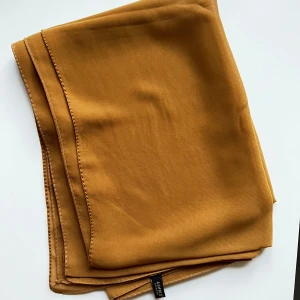Slöja/hijab - Säljer en slöja köpt från Turkiet, i märket Asmira. Tyget är chiffong. Färgen är mer som senapsgul i verkligheten. Vid intresse kan skicka måtten. 
