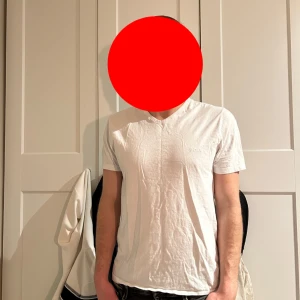 Vit v-ringad t-shirt från Boss - Säljer en stilren vit t-shirt från Boss med v-ringning. T-shirten har korta ärmar och en diskret logga på bröstet. Perfekt för en clean och enkel look.