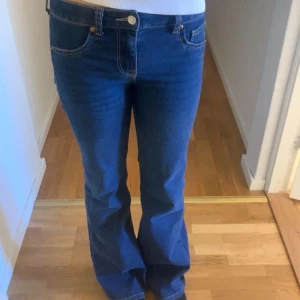 Blå bootcut jeans - Säljer ett par klassiska blå bootcut jeans med normal passform. Jeansen har medelmidja och tydliga kontrastsömmar. Perfekta för dig som gillar en tidlös stil med lite utsvängda ben.