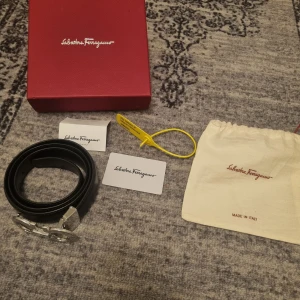 Salvatore Ferragamo bälte - Säljer ett svart bälte från Salvatore Ferragamo med en ikonisk silverfärgad spänne. Skärpet är i storlek 42/105. Kommer med originalförpackning. Tyvärr inget kvitto men köpt från miinto. Billigare vid snabb affär