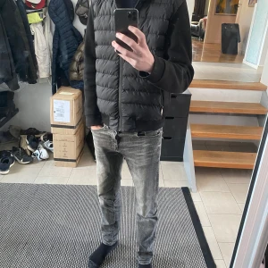 Svart ”cardigan” från 19v69 by Versace  - Säljer en svart dunväst från Italia 19v69 med huva och dragkedja. Västen har quiltad framsida och släta ärmar, samt två fickor med dragkedja. Perfekt för lager-på-lager och stilren look. Köpt ny aldrig använd. Passar runt 180cm Köpt på johnells för 2500kr