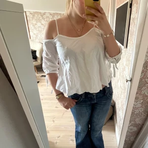 Vit offshoulder topp med knytärmar - Säljer en vit offshoulder topp med tunna axelband och trekvartsärmar med knyt i ändarna.💞