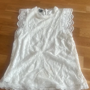 Vit spetsblus från Pieces - Superfin vit blus från Pieces i spets med vackra detaljer längs ärmarna och nederkant. Ärmlös modell med rund halsringning och helspets över hela toppen. Perfekt för sommarens alla tillfällen! Nypris 400
