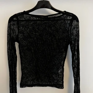 Svart mesh topp med lång ärm - Säljer en svart mesh topp med lång ärm. Tunt och genomskinligt material som ger en cool och edgy look. Perfekt att styla lager på lager eller till ett statement-plagg.