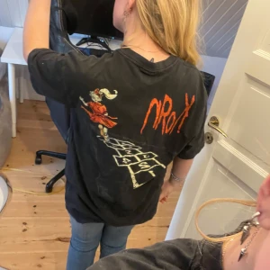 Svart t-shirt med tryck från H&M - Svart oversized t-shirt från H&M med coolt tryck på ryggen som föreställer en figur och hopphage samt texten 'Follow the Leader'. T-shirten har korta ärmar och är tillverkad i bomull. Perfekt för en avslappnad stil.