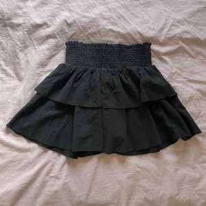 Svart volangkjol - Supersöt svart kortkjol med dubbla volanger. Kjolen har en luftig och flowy känsla, perfekt för att styla med crop tops eller stickade tröjor nu i sommar. Enkel att dra på tack vare resåren i midjan och går att vika ner och göra ännu mer Low waist💞💞 Är stretchig så passar både Xs-S-M