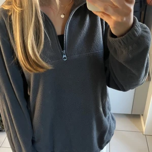 Lila fleece-tröja med dragkedja - Mysig lila fleece-tröja med halv dragkedja framtill. Enkel och stilren design utan synliga loggor eller mönster.