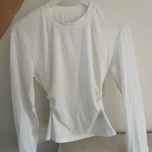 Vit långärmad topp - Säljer en enkel och stilren vit långärmad topp. Modellen är figursydd med rund halsringning. Perfekt basplagg för garderoben!