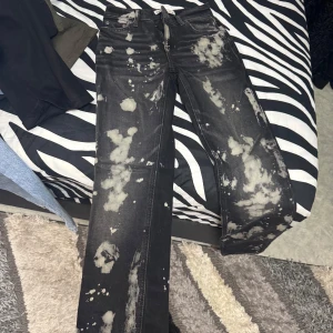 Svarta jeans med blekta detaljer från Zara - Coola svarta jeans från Zara med unika blekta mönster över hela byxorna. Modellen har raka ben och klassisk femficksdesign. Perfekta för dig som vill sticka ut med en edgy stil.