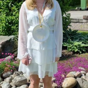 Vit volangklänning med långa ärmar - Söt vit klänning med långa, transparenta ärmar och volangdetaljer i kjolen. Klänningen har v-ringning och är perfekt för somriga tillfällen. Lätt och luftig känsla.