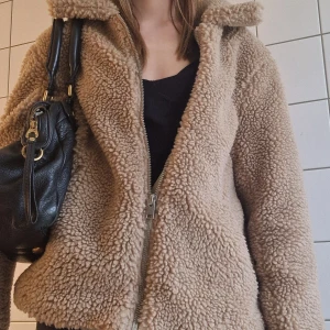 Teddyjacka  - Mysig beige teddyjacka med krage och dragkedja framtill. Nypris: ca 550 Mitt pris: 299. Använd ca 5 ggr.
