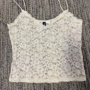 Vit spetslinne med blommönster - Säljer ett vitt linne från H&M med tunna axelband och som har ett blommigt spetsmönster. Jättefin att ha över tillexempel en bikini nu på sommaren💕