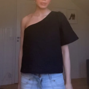 One shoulder topp - Jättefin svart one shoulder topp med lite blommigt mönster från vila, storlek 34 