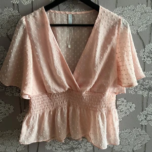 Ljusrosa blus med volang från Amisu - Liten och kort i storleken, tror den passar storlekarna M/L❣️Supersöt ljusrosa blus från Amisu med v-ringning, volangärmar och smockad midja. Tunt, prickigt tyg med struktur och lätt glans. Perfekt för vår och sommar💐