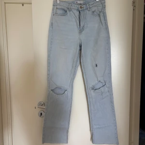 Ljusblå slitna jeans från Zara - Ljusblå jeans från Zara med raka ben och slitna detaljer vid knäna. Klassisk femficksmodell med gylf och knapp. Perfekta för en avslappnad stil.