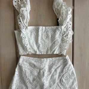 Vitt sett med kjol och topp med volang och broderi - Superfin vit kort kjol med broderade detaljer och volang längst ner, från Zara i storlek 164. Toppen är också med broderat mönster från Zara i storlek S, men banden är något förkortade. Så gulligt sett och mycket efterfrågat! 