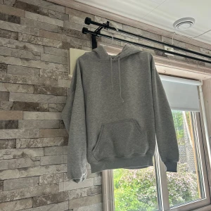 Grå hoodie från Bik Bok XS - En basic grå hoodie från Bik Bok i storlek XS. Tröjan har huva med snörning, magficka och långa ärmar. Perfekt för chill dagar eller när du vill ha en enkel och stilren look. Mjuk insida och klassisk passform.