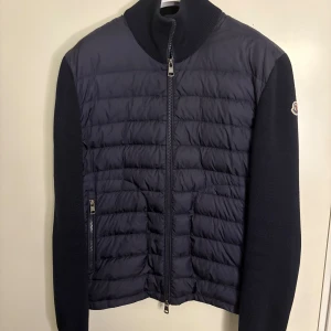Moncler Cardigan Navy - Moncler Cardigan Navy i storlek M. Väldigt fint skick, lite slitet vid muddarna. Inget som märks vid användning.