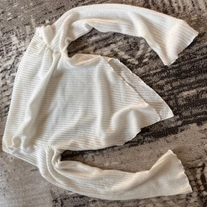 Vit ribbad långärmad tröja - Säljer en vit långärmad tröja med ribbad struktur. Tröjan har en enkel och clean look med mjukt material och raka ärmar. Perfekt för lager-på-lager eller att bära som den är. Passar dig som gillar minimalistisk stil.
