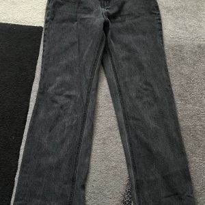 Svarta  jeans från Vero Moda - Snygga svarta jeans från Vero Moda med lite utsvängda ,passform. Jeansen är i klassisk denim och har en enkel design utan slitningar eller detaljer. Perfekta till sneakers eller boots för en clean look.